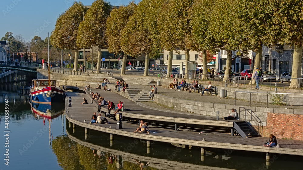 Naklejka premium People hanging out on a quay along river Lys in Portus Ganda, Ghent