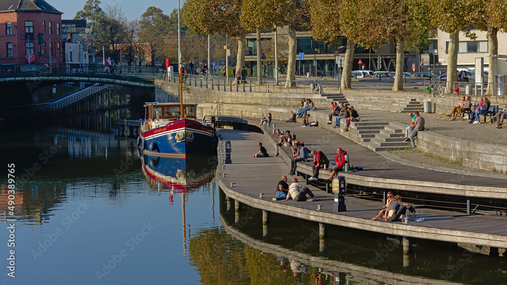 People hanging out on a quay along river Lys in Portus Ganda, Ghent