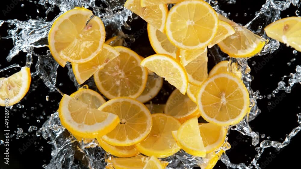 Super slow motion shot of rotating exploded lemon slices with splashing water on black at 1000fps.