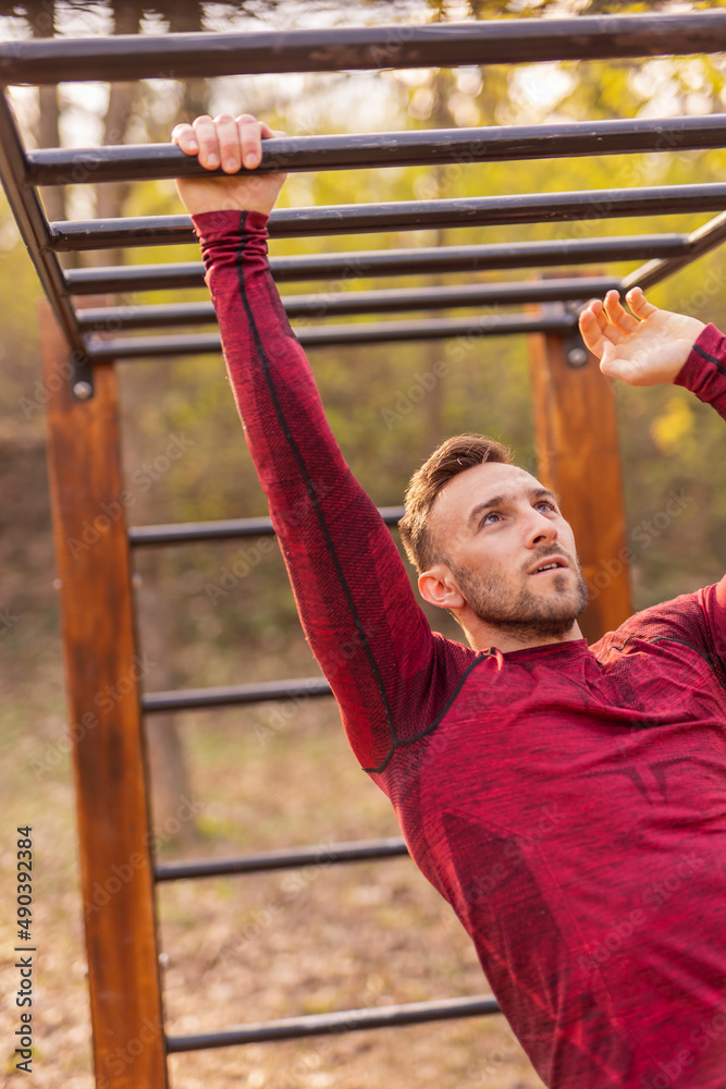Man working out on monkey bars in street workout park Man working out on monkey bars in street workout park