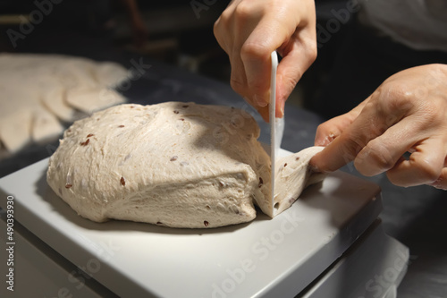 Women's hands carry out actions with raw bread. Dough before dipping into a bakery oven