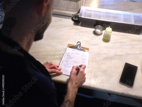 Chef checking the list to do written on a piece of paperr in the kitchen
