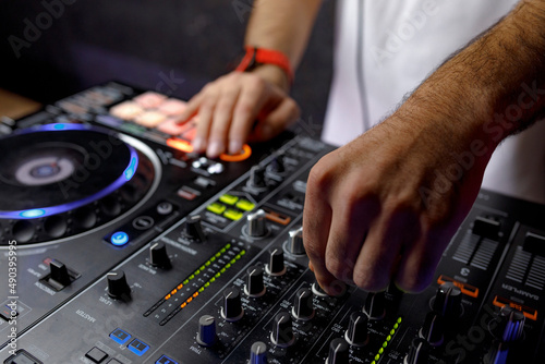 DJ creating music on modern console mixer in night club, closeup © Evgeniy Bezborodov