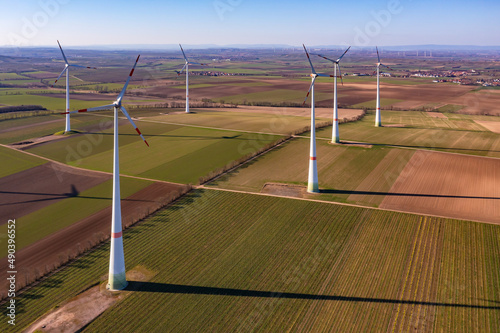 Ein Windpark mit Windr  dern zwischen Feldern von hoch oben aus der Luft gesehen