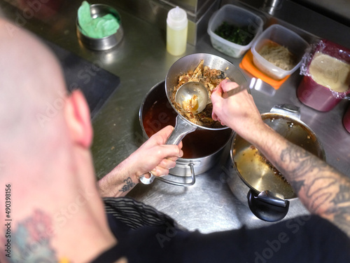 Chef pressing food into a colander to make some sauce