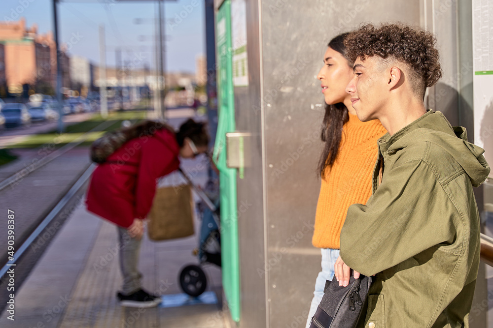 teenage couple waiting for the train or bus/shuttle or bus at a station. concept of commuter and transport