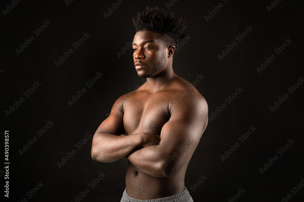 Naklejka premium portrait of an african male with muscles on a black background