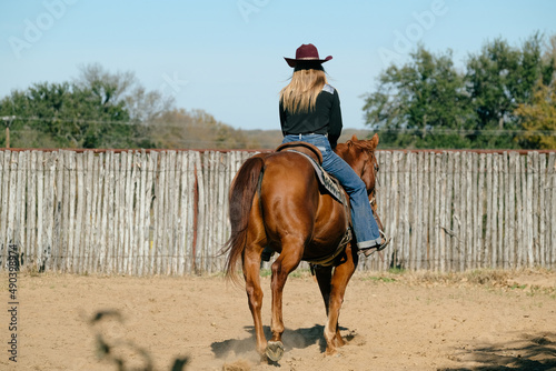 Cowgirl riding horse through arena outdoors for western lifestyle.