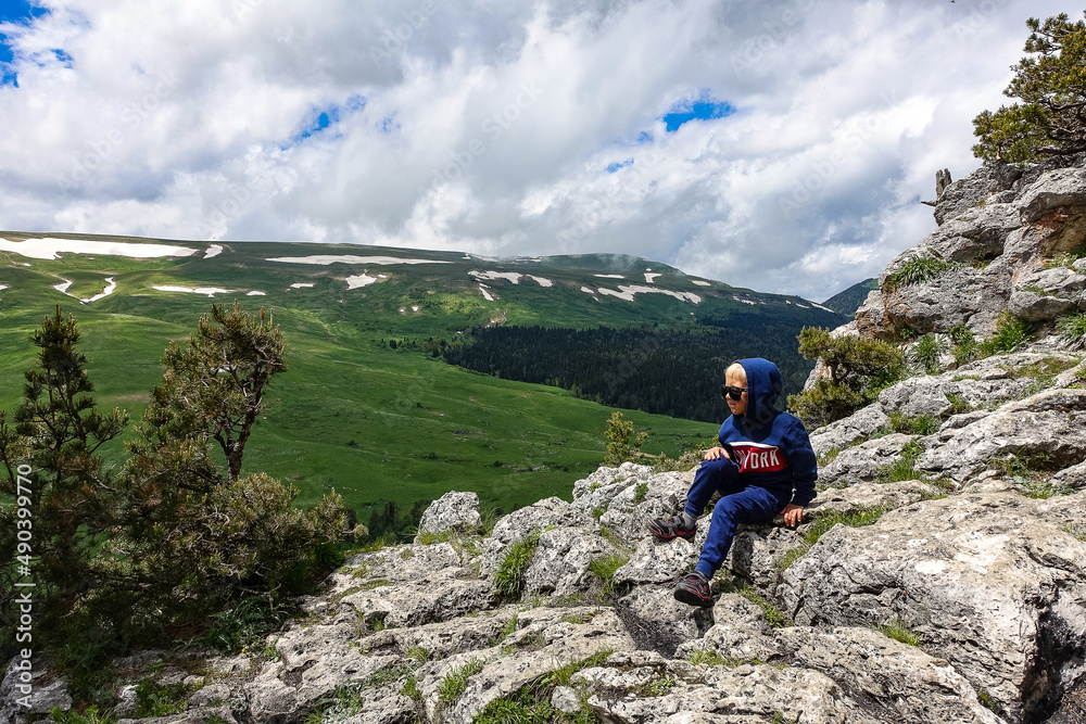 A little boy on the background of the alpine meadows of the Lago-Naki plateau in Adygea. Russia. 2021. A little boy on the background of the alpine meadows of the Lago-Naki plateau in Adygea. Russia. 2021.