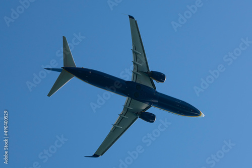 Blue plane seen just below, flying over blue sky. Copy space over blue sky.