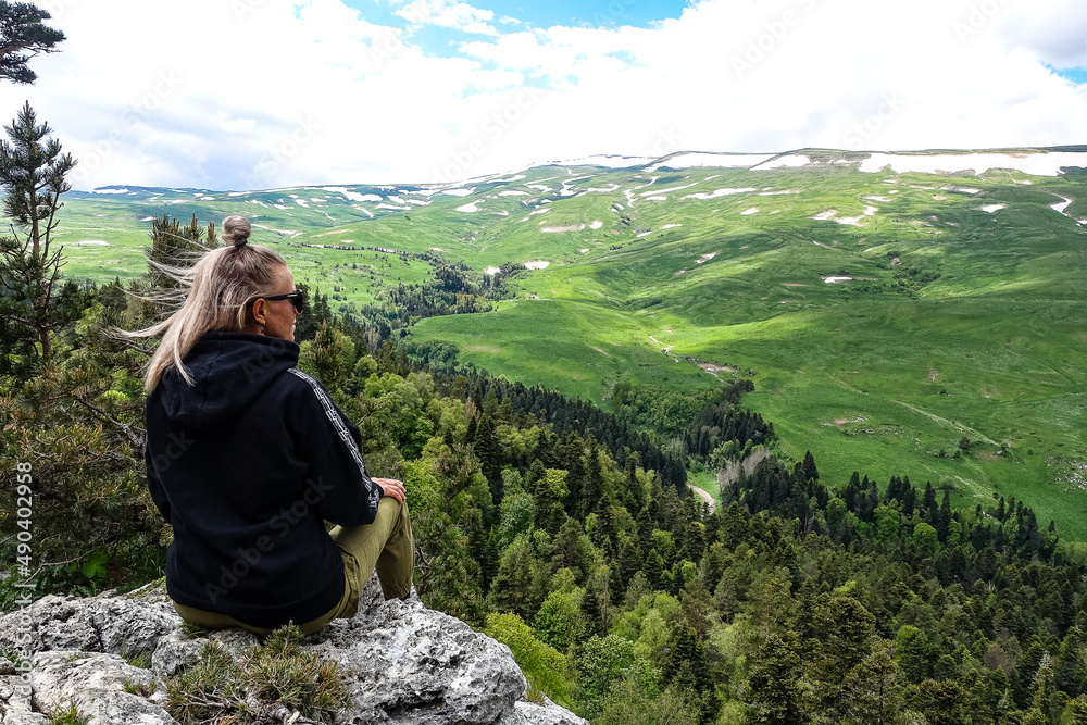 Naklejka premium A girl on the background of alpine meadows of the Lago-Naki plateau in Adygea. Russia. 2021.
