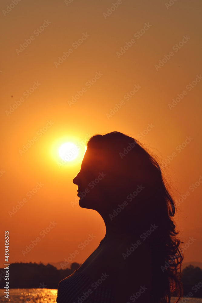 Woman Silhouette with Orange Sunset Sky and Sea in the Background. Orange Sea Sunset Woman Shadow Woman Silhouette with Orange Sunset Sky and Sea in the Background. Orange Sea Sunset Woman Shadow
