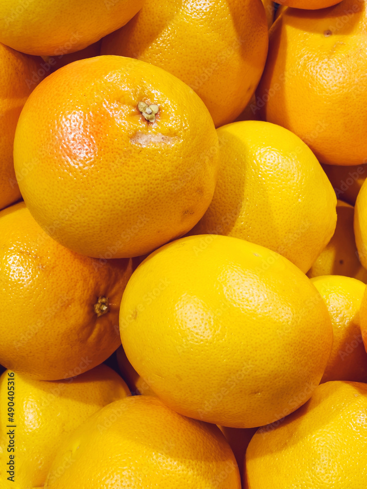 Many orange grapefruit stacked on a supermarket shelf Many orange grapefruit stacked on a supermarket shelf