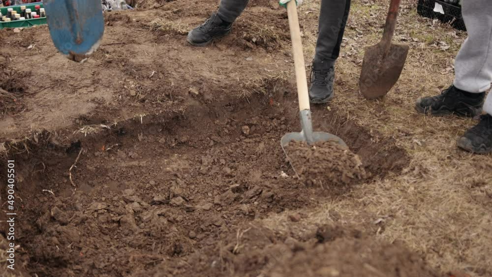 Freshly dug grave tool at cemetery, a close-up. Grave, top view, just been digged, spade by edge. Digging. Pit in ground. Shovel lies in pit. Digging hole with spade in field
