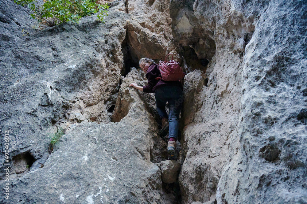 A Caucasian female hiker climbing up the rocky cliff A Caucasian female hiker climbing up the rocky cliff