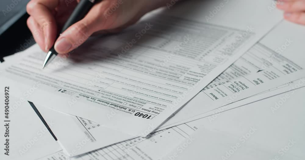 Woman Reads Irs Us Individual Income Tax Form 1040 in tax time. Closeup view. Individual Income Tax Return Form 1040 Woman Reads Irs Us Individual Income Tax Form 1040 in tax time. Closeup view. Individual Income Tax Return Form 1040