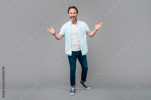 Happy senior man in casual gesticulate with open arms grey background, welcome