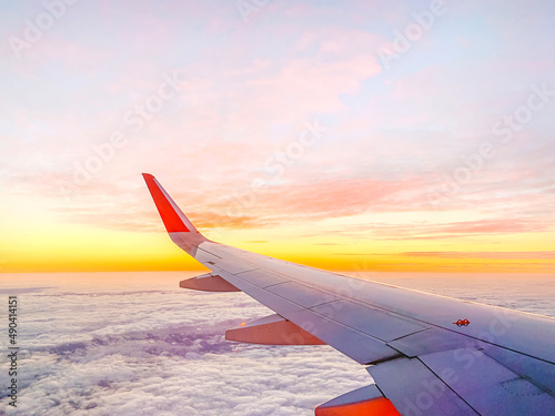 Airplane wing in the sky at beautiful sunset, airplane flight in the sky with copy space