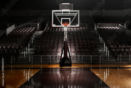 Empty basketball arena with dramatic lighting, view from free throw line in front of goal on the court