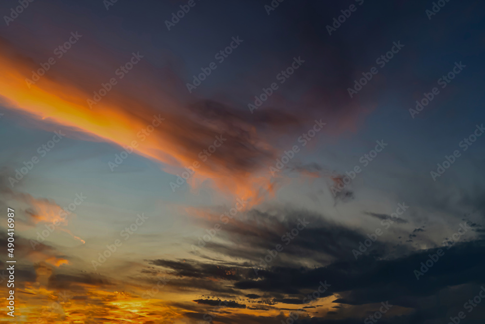 Panorama of dramatic colorful sunset with dark and bright clouds.