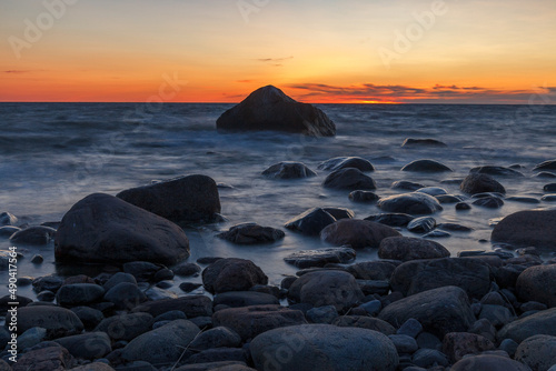 Rocky shore with stones sinking in the sea water. Sunset, long exposure. Baltic sea. Purekkari neem, Estonia.