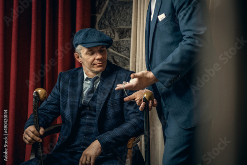 Two men in stylish suits confer,  england in 1920s theme. Peaky blinders style. photo