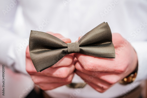 Brown bow tie in the hands of the groom. Bow tie in the hands of a man
