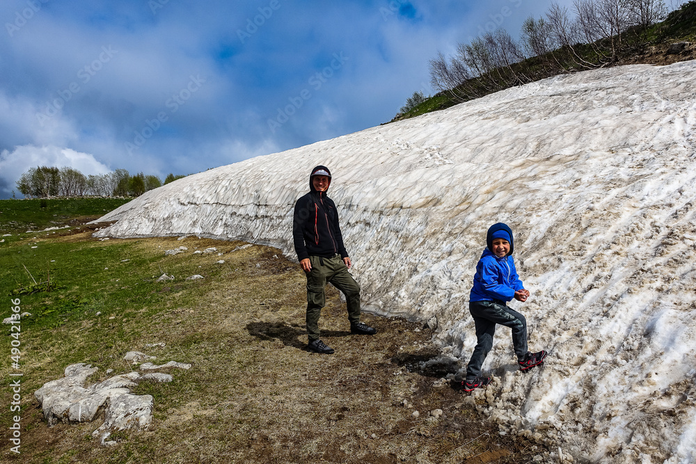 Fototapeta premium A man with a child near a glacier on the Lago-Naki plateau. Snow in Adygea. Russia. 2021.