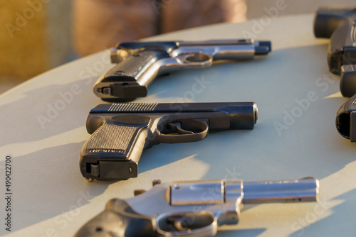 A gun on the table among the weapons, selective focus. Crime news background. photo
