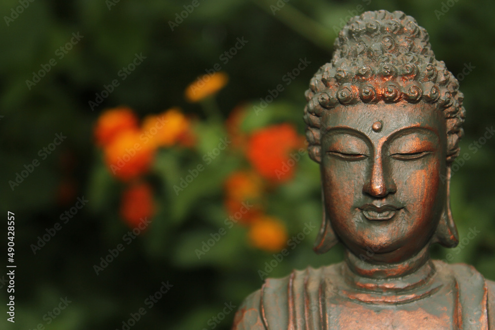 Buddha Statue in Garden with blurred flowers in background