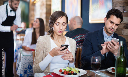 Portrait of satisfied man and woman in the restaurant with mobile phones