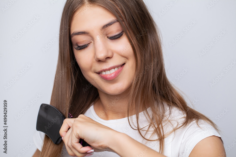 Attractive smiling woman brushing her long straight hair Attractive smiling woman brushing her long straight hair