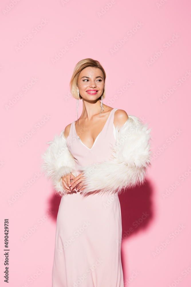cheerful blonde woman in slip dress and faux fur jacket on pink. cheerful blonde woman in slip dress and faux fur jacket on pink.