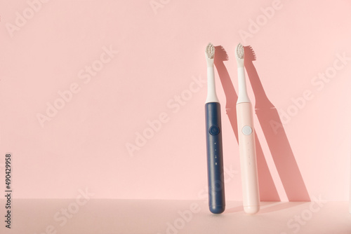 Two new modern ultrasonic toothbrushes. Dental care supplies on pink pastel background. Oral hygiene, dental and gum health, healthy teeth. Dental products Ultrasonic vibration toothbrush.