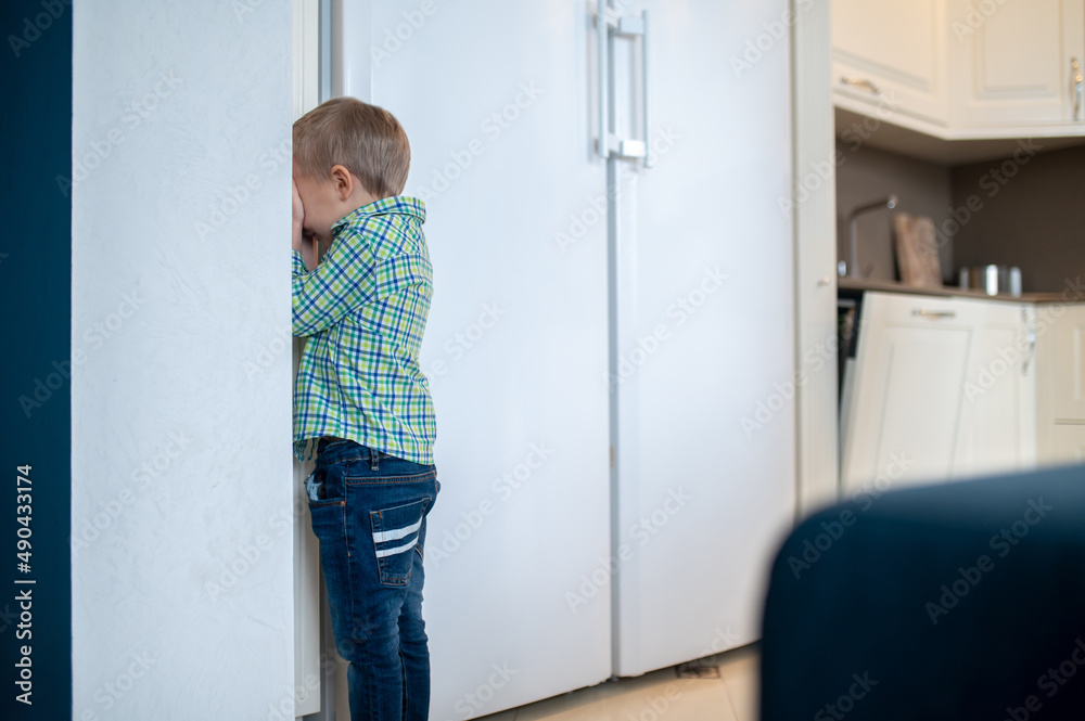 Boy playing hide and sick in the kitchen Boy playing hide and sick in the kitchen