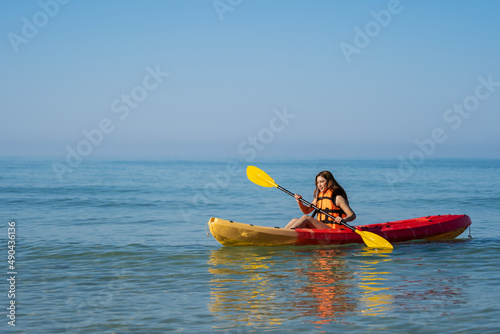 woman in life jacket paddling a kayak boat in sea