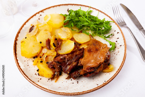 Traditional french food, duck confit with stew potatoes and greens on a plate in a cafe photo