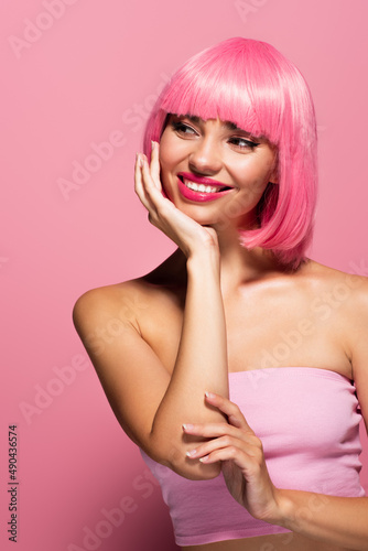 happy young woman with bangs and colored hair isolated on pink.