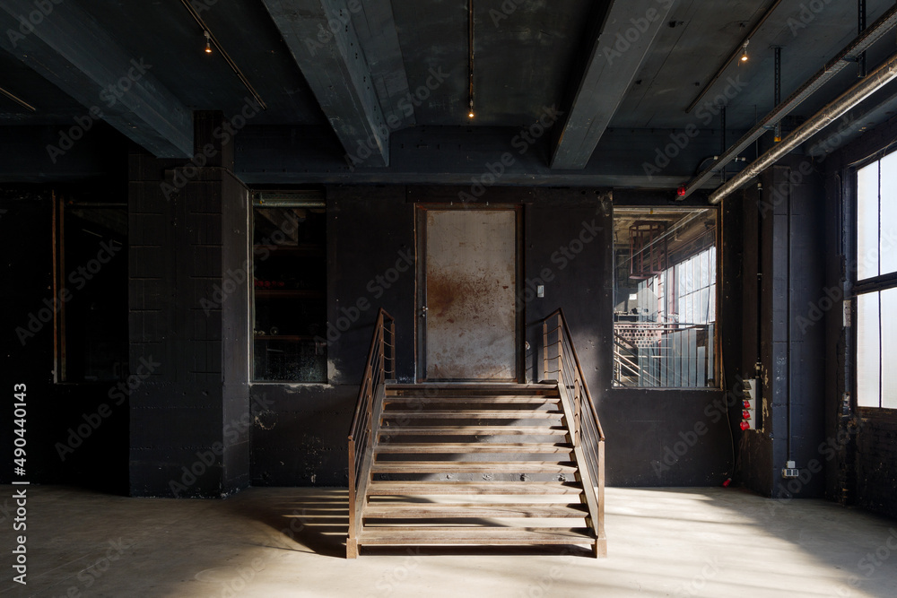 Interior view of industrial loft empty room with rusty central staircase in the middle of the room. 