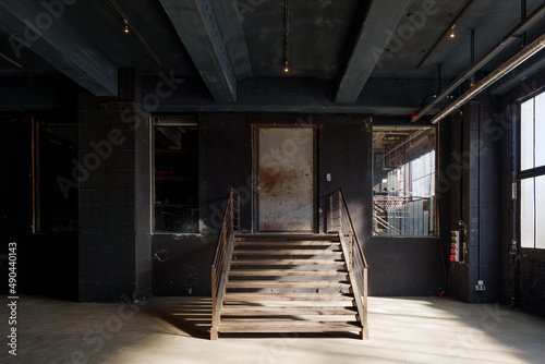 Interior view of industrial loft empty room with rusty central staircase in the middle of the room. 