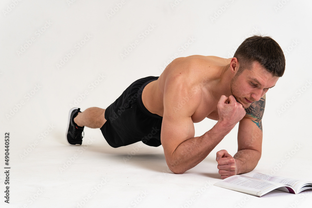 Bodybuilder reads the book on a white background isolated at the bottom of his head on his hands bodybuilder handsome macho, muscle glasses reader adult, fit. Isolated winner gym, vision tan Bodybuilder reads the book on a white background isolated at the bottom of his head on his hands bodybuilder handsome macho, muscle glasses reader adult, fit. Isolated winner gym, vision tan