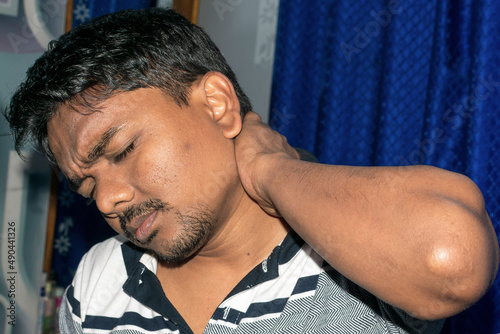 Cervical spondylitis, osteomyelitis and fibromyalgia in Indian man. He use hand touching neck back on isolated white background use for health care concept. photo