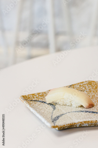 Yellotail Hamachi sushi on Japanese style tile plate, wihite table background, vertical image with copy space. photo