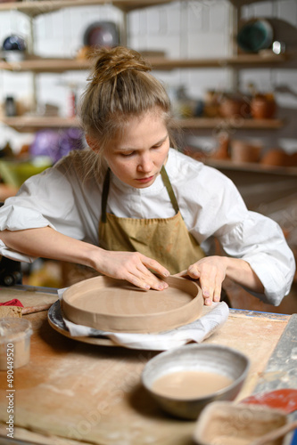 Girl make clay plate in ceramic workshop