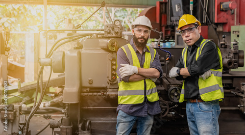 Engineer male team wearing safety helmet and vest standing action in front of heavy macinery in industrial factory photo