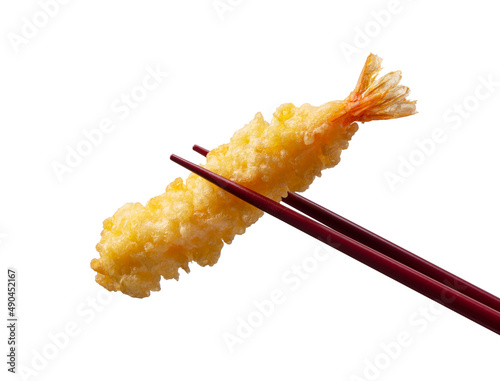Shrimp tempura lifted with chopsticks against a white background.