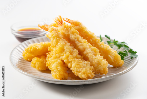 Shrimp tempura on a plate placed on a white background.