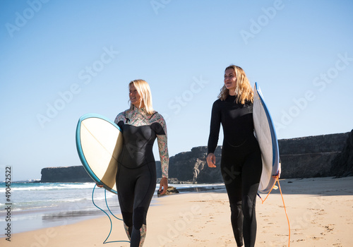 Photography Caucasian surfer women on the beach looking to the waves