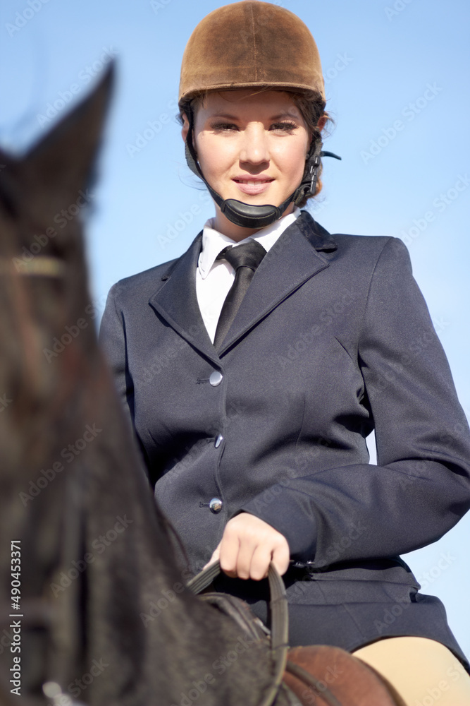 He rides like the wind. Low angle portrait of a young woman sitting on her horse. He rides like the wind. Low angle portrait of a young woman sitting on her horse.