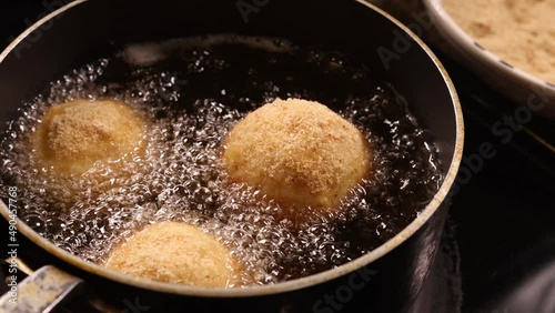 Three Italian arancini rice balls deep frying in hot boiling oil. photo